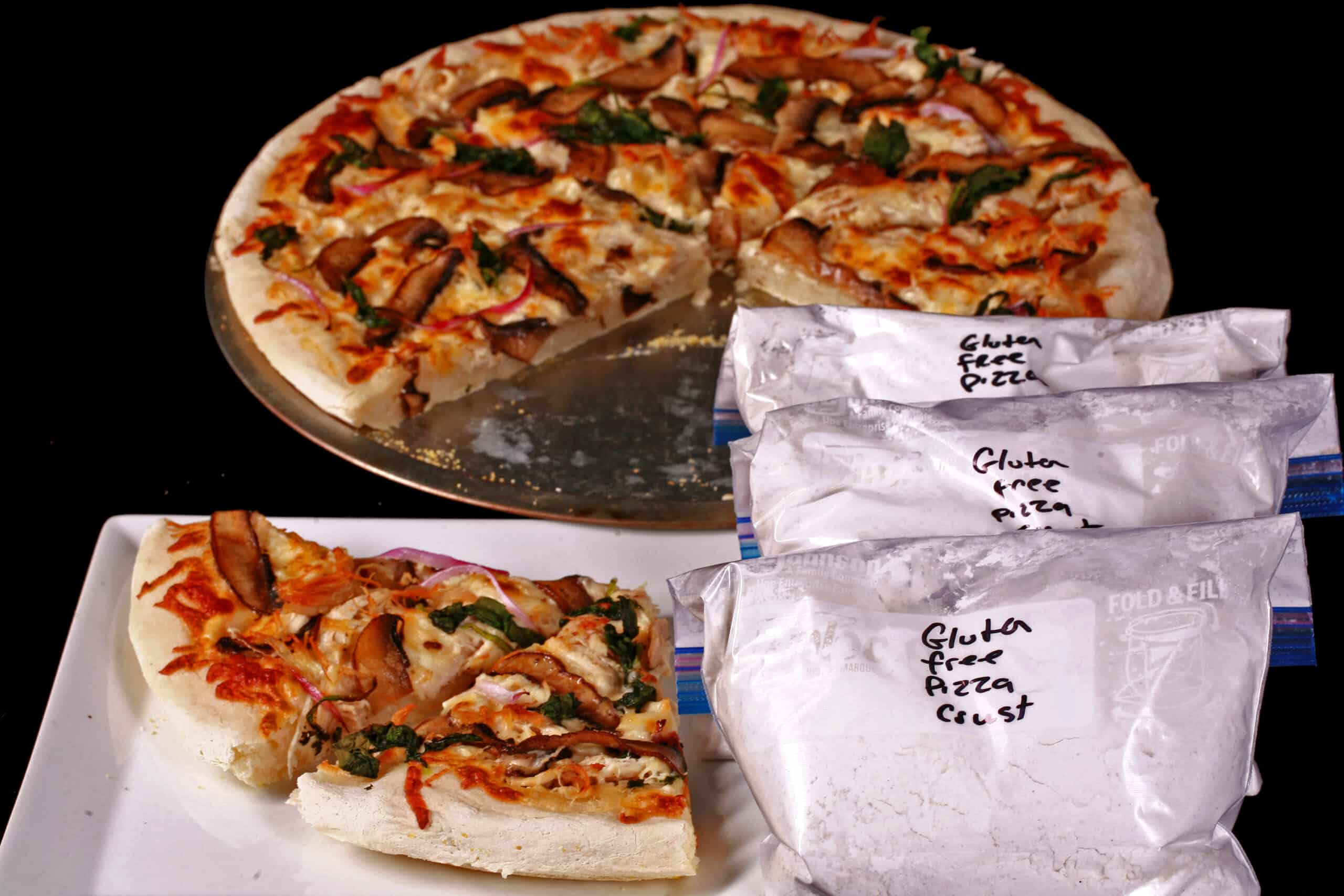 Several freezer bags of homemade gluten-free pizza dough mix, with baked pizza on a plate.