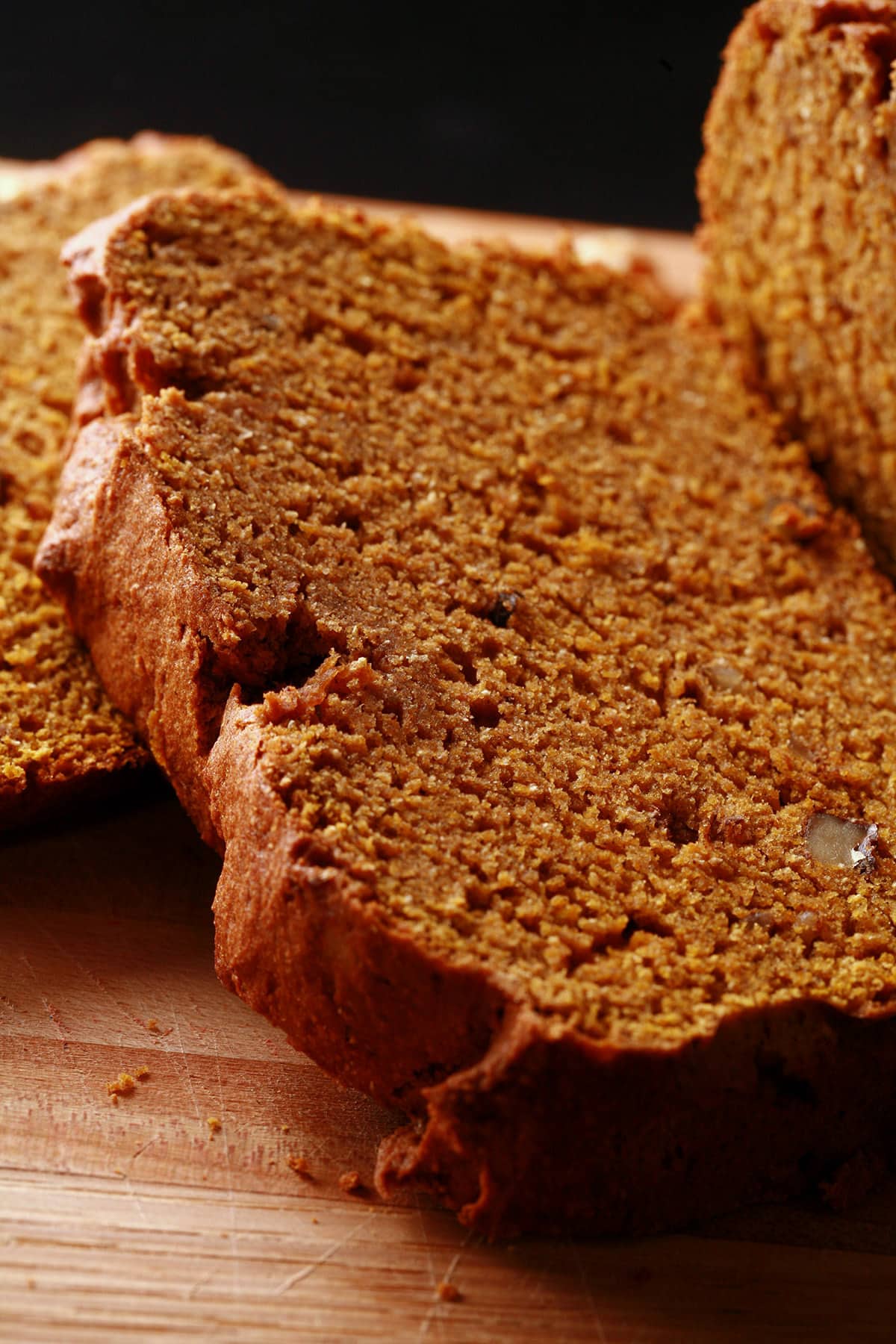 A loaf of gluten-free pumpkin spice bread on a cutting board, sliced.