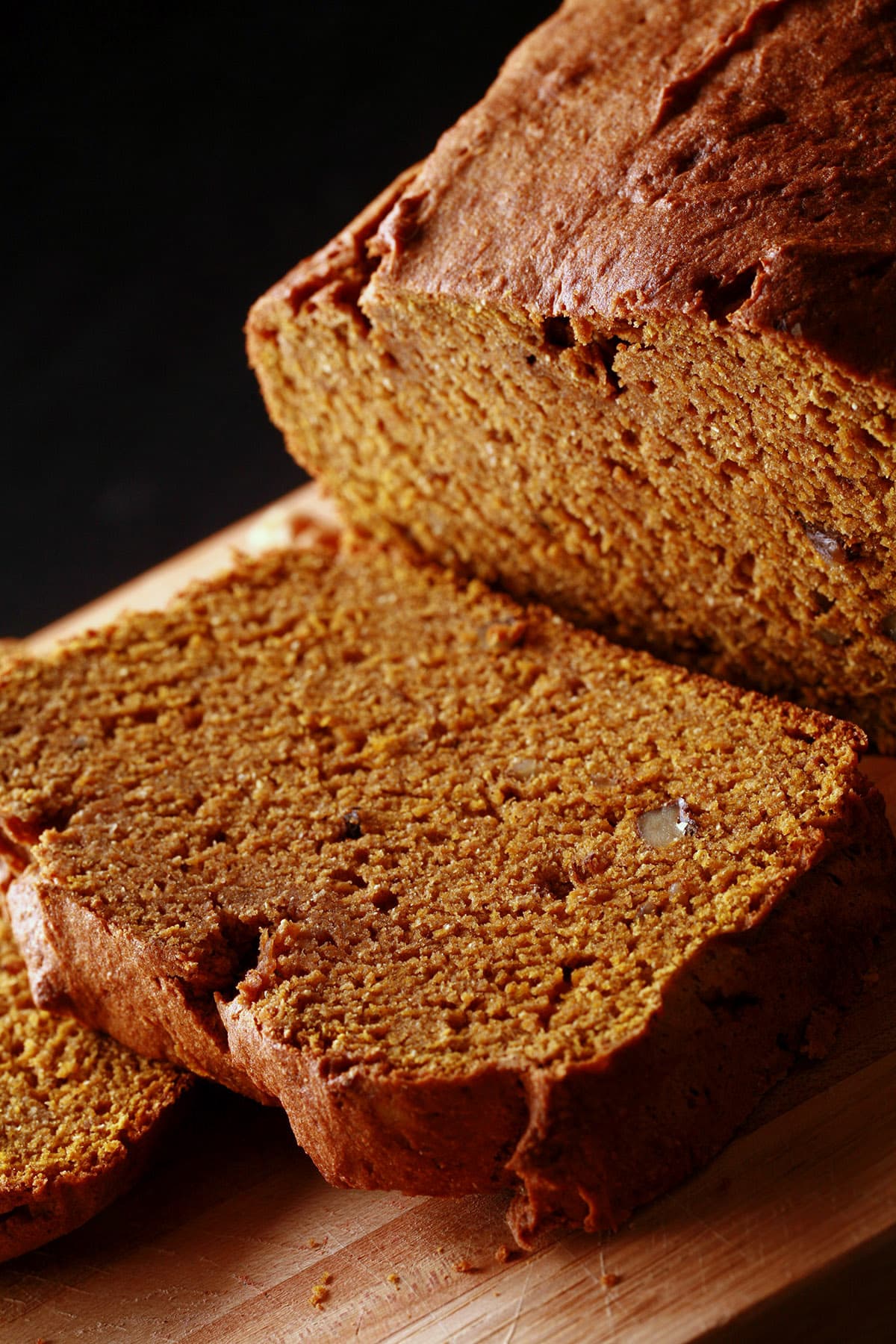 A loaf of gluten free pumpkin bread on a cutting board, sliced.