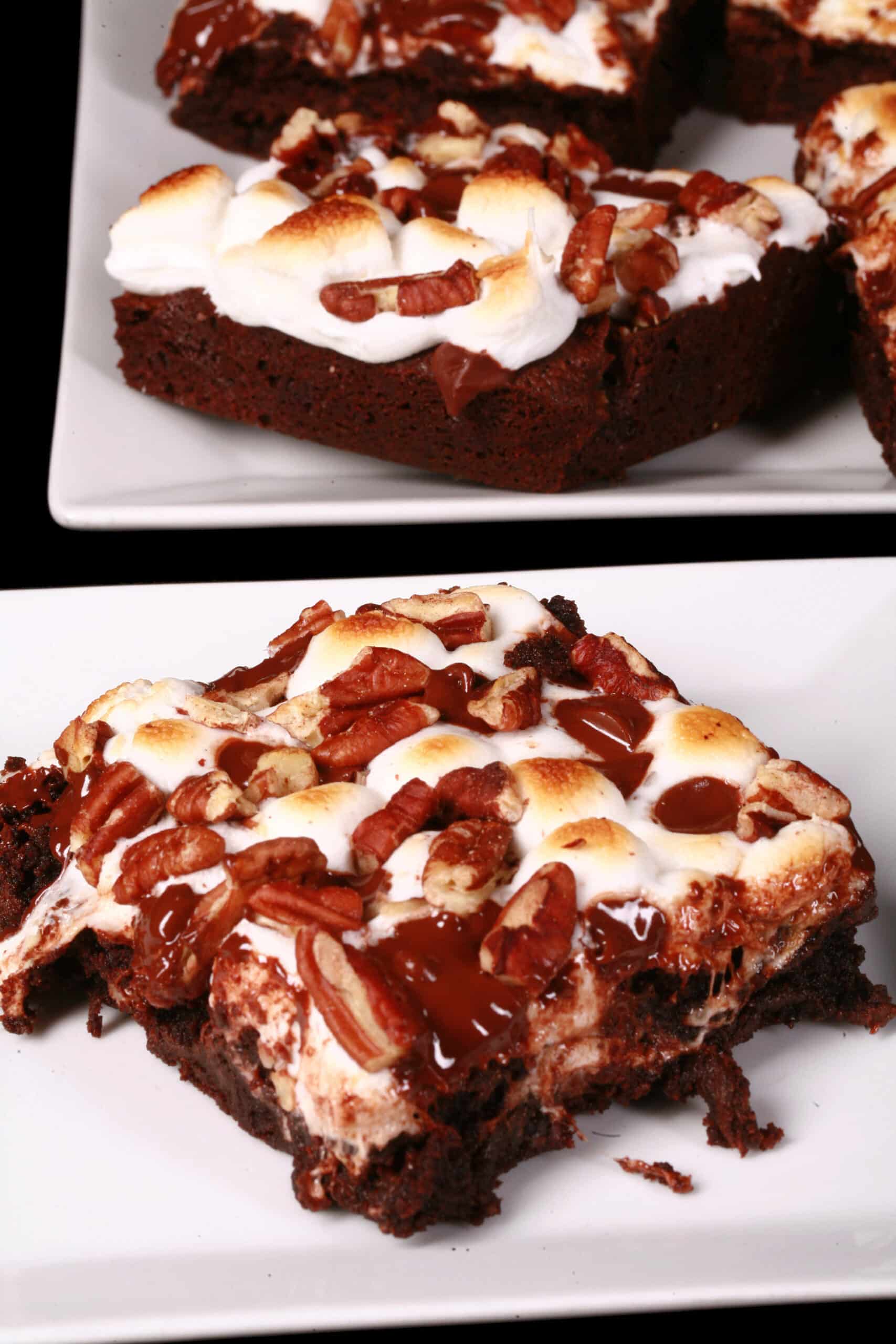 A plate of gluten free rocky road brownies, topped with toasted mini marshmallows, pecans, and chocolate chips.
