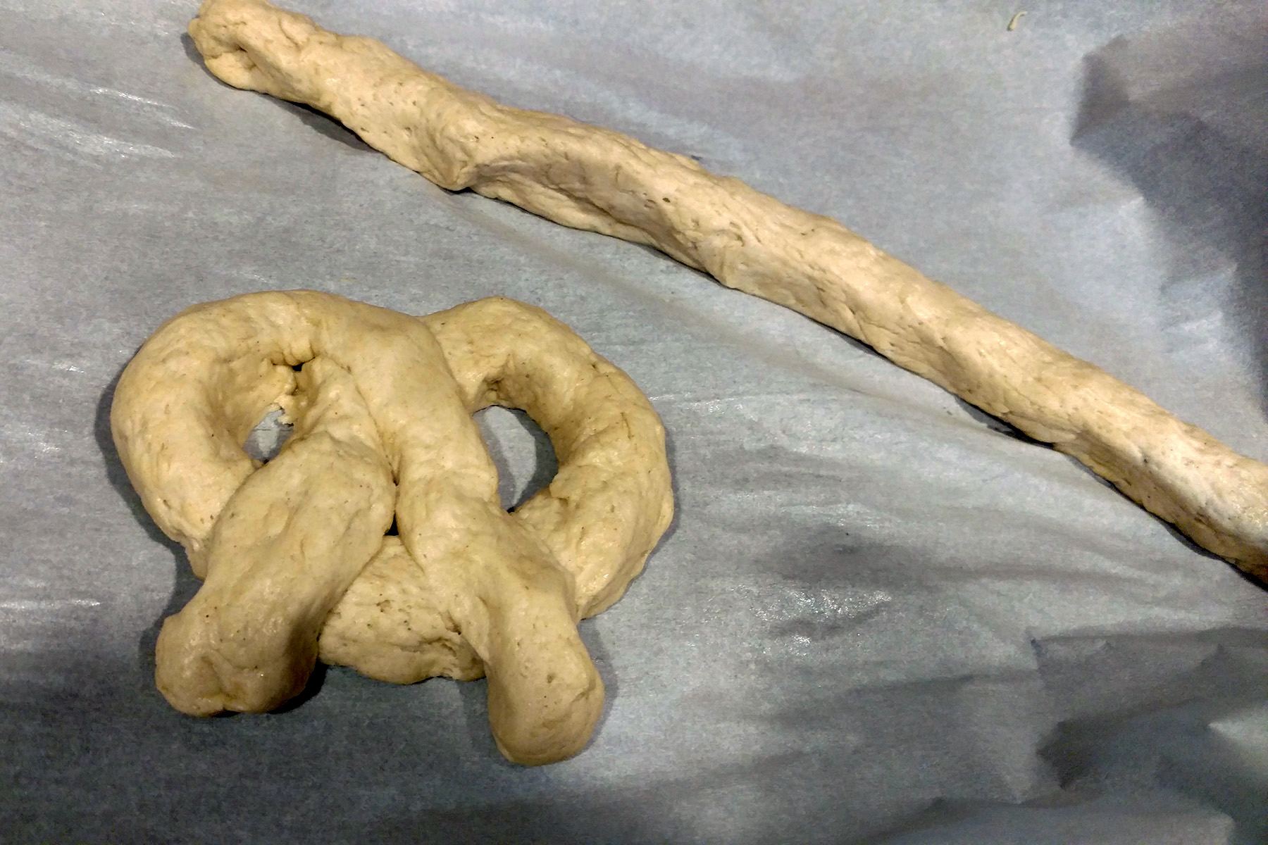 A long snack of pretzel dough, and a pretzel formed from that dough,