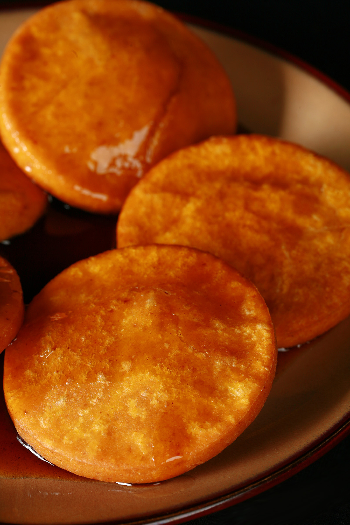 A plate of gluten free sopaipillas pasadas, with sauce drizzled over them.