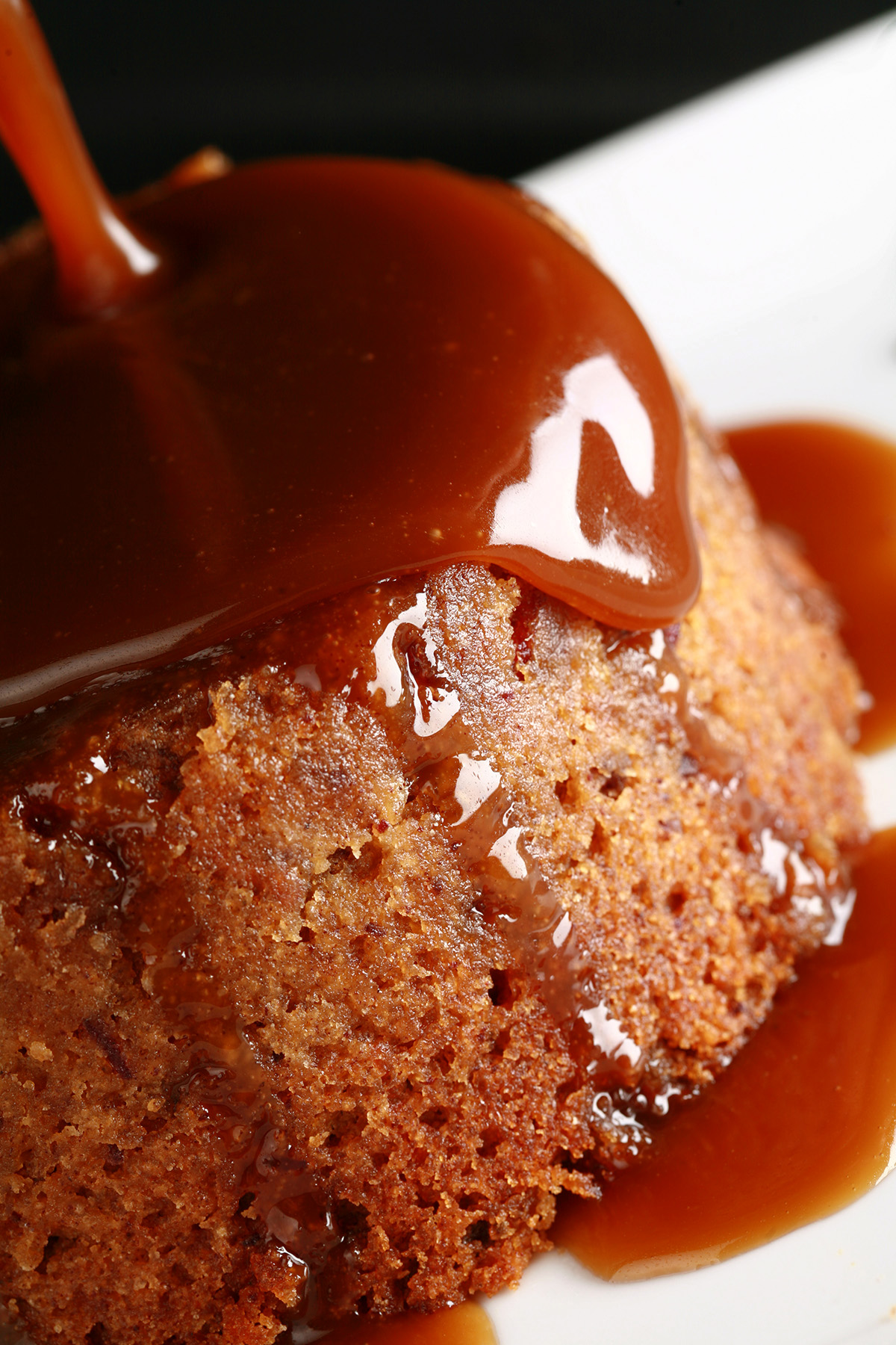 A gluten free sticky date pudding with toffee sauce being poured over it.
