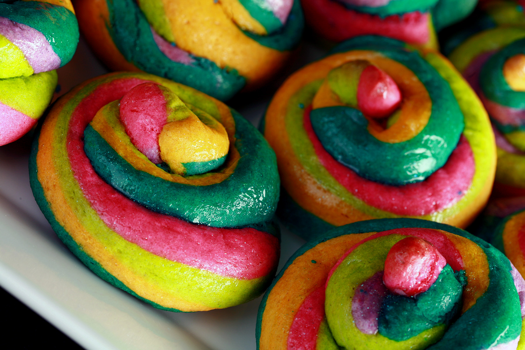 A close up view of a pile of gluten-free unicorn poop cookies. They are brightly coloured cookie "poops" made from brightly coloured twists of cookie dough.