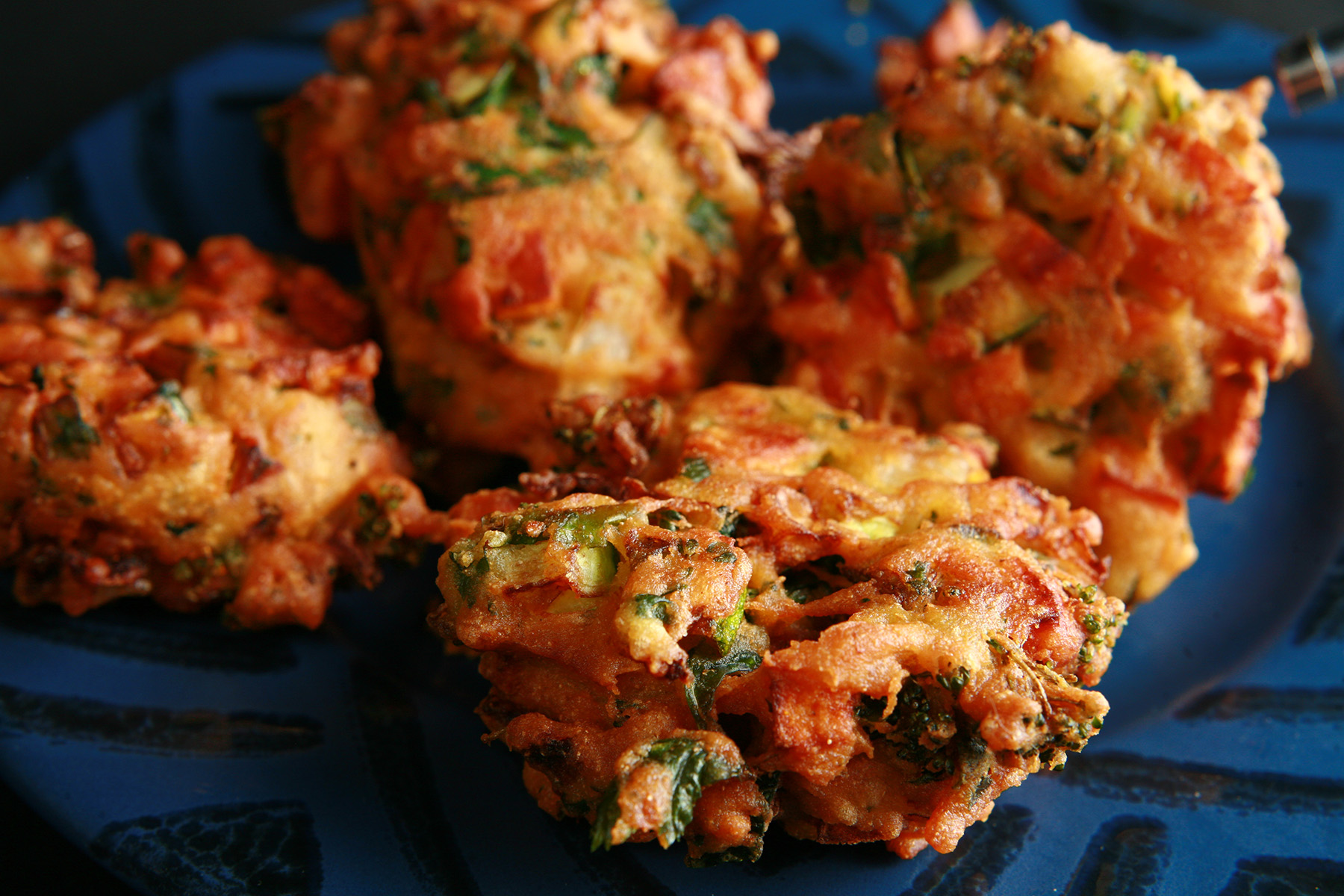 Several Mixed vegetable pakora, on a blue plate.