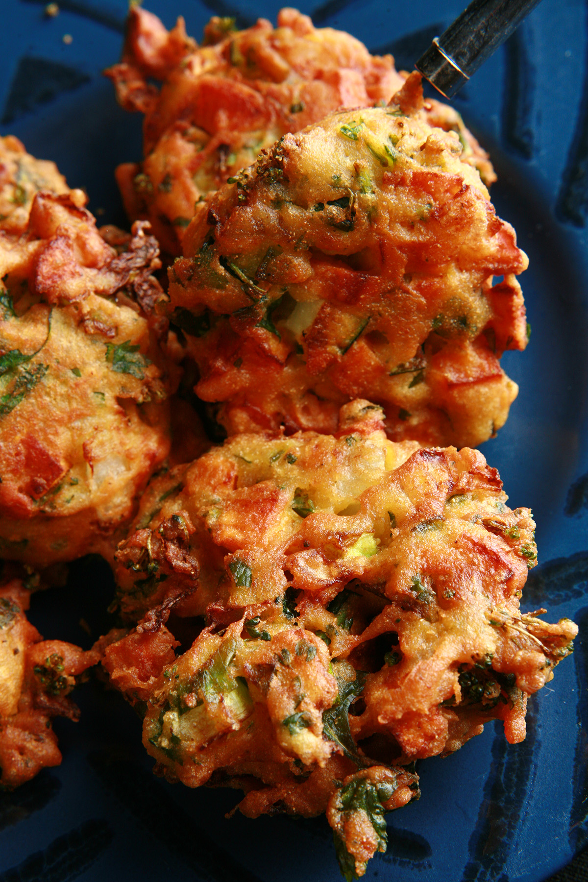 Several Mixed veggie pakora, on a blue plate.