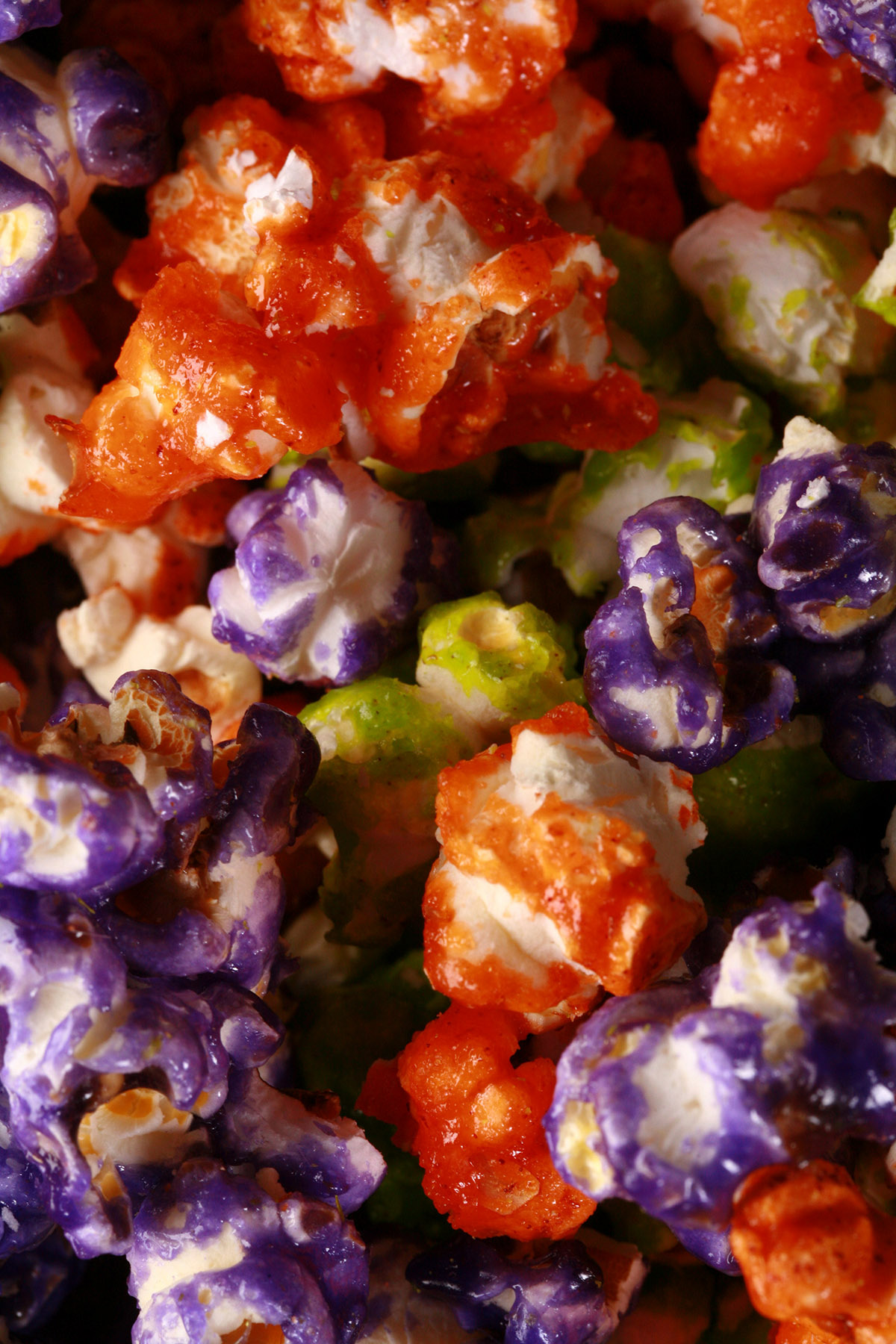 A close up of Halloween glazed popcorn - orange, purple, and lime green mixed together.