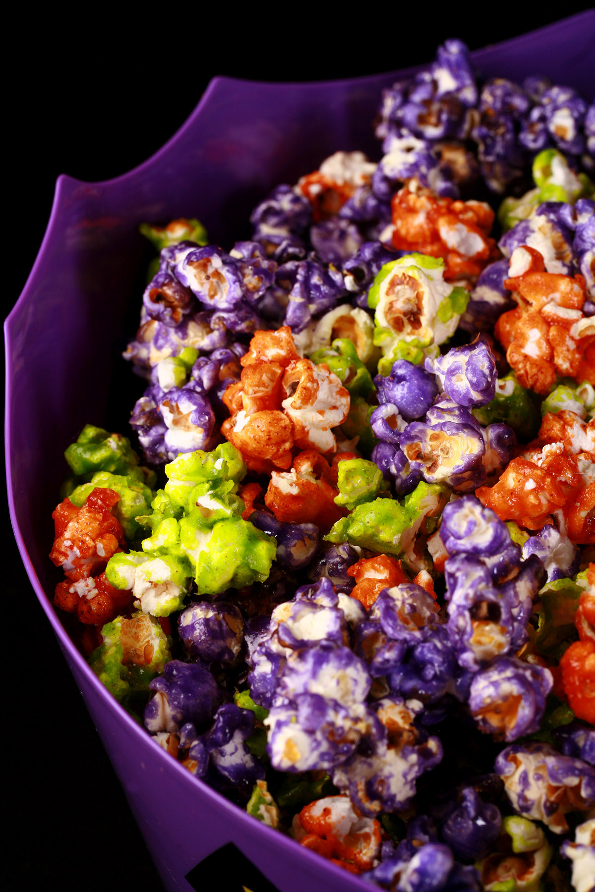 A bowl of Halloween glazed popcorn - orange, purple, and lime green mixed together.