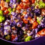 A bowl of Halloween popcorn - orange, purple, and lime green glazed popcorn, mixed together.