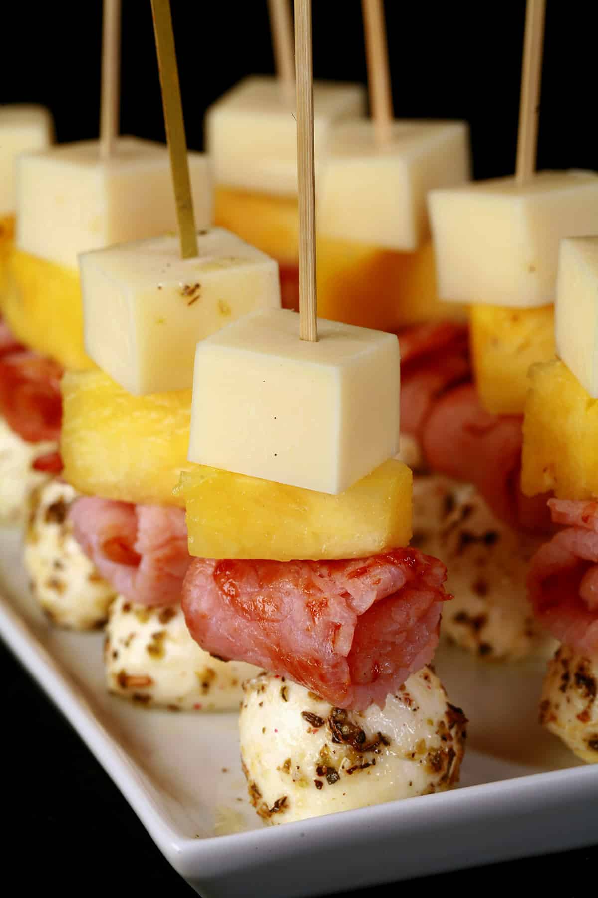 A tray of hawaiian pizza skewers - pineapple, back bacon, and 2 kinds of cheese.