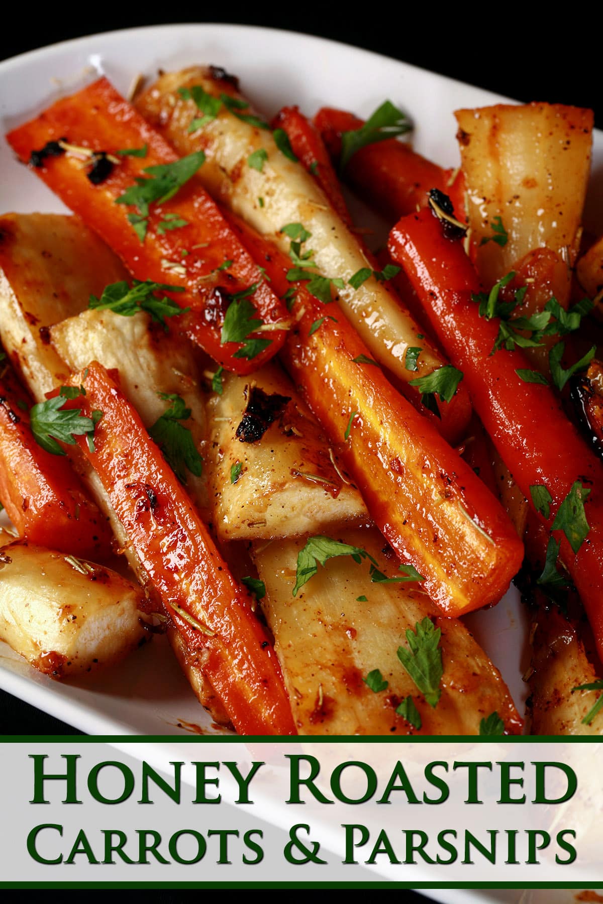 A platter of honey roasted parsnips and carrots, sprinkled with parsley.