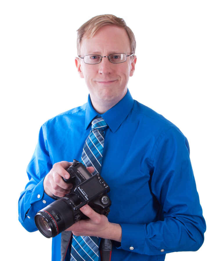 A middle aged blond man holding a camera.