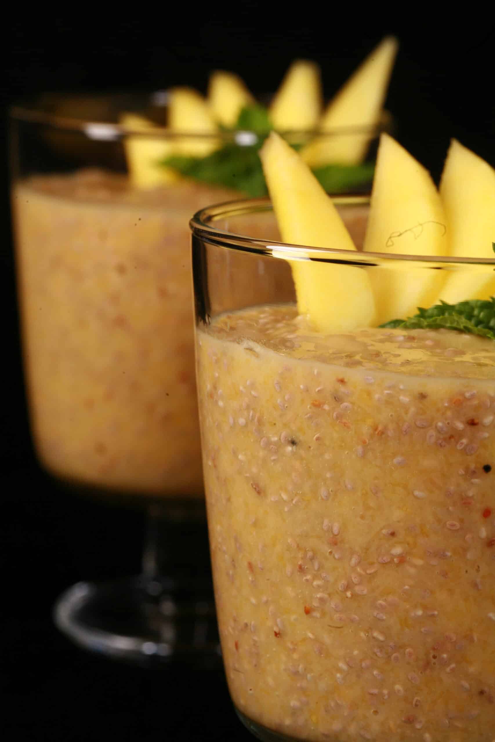 2 glasses of mango chia seed pudding, garnished with mango slices and fresh mint leaves.