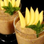 2 glasses of mango chia pudding, garnished with mango slices and fresh mint leaves.