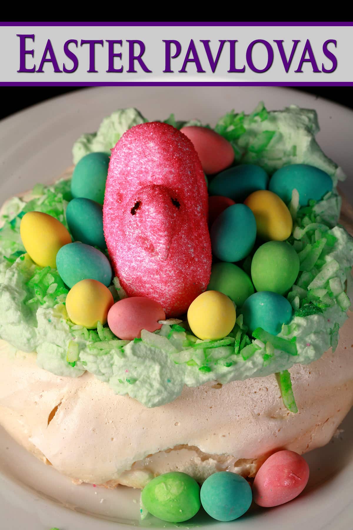 A single mini Easter pavlova, topped with green coconut and cadbury mini eggs and a pink Peeps marshmallow.