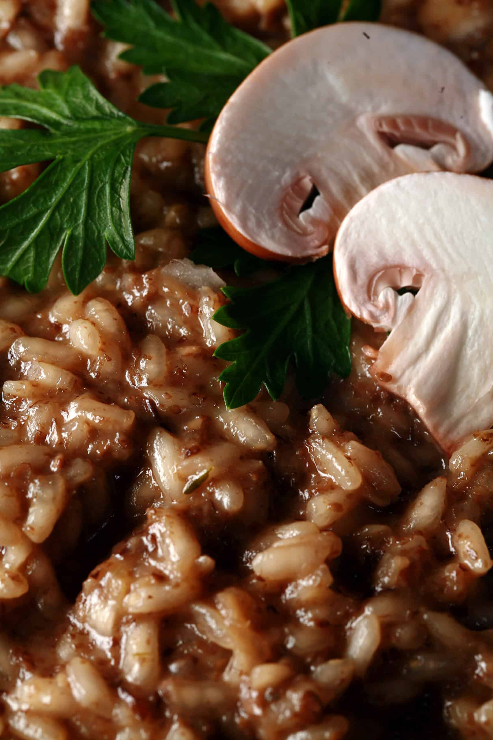 A plate of creamy mushroom risotto, garnished with parsley leaves and sliced mushrooms.