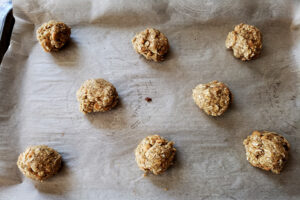 Balls of gluten-free oatmeal cookie dough, arranged on a parchment lined baking sheet.