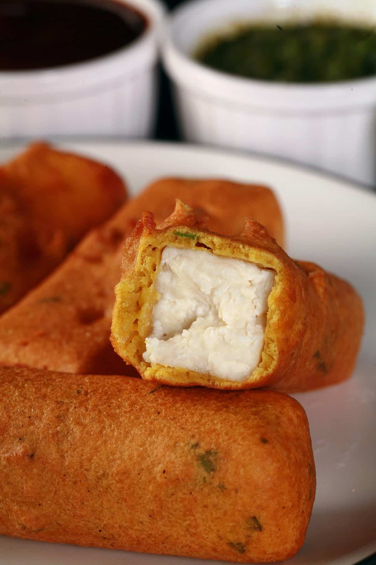 A plate of paneer pakora, with one bitten in half.