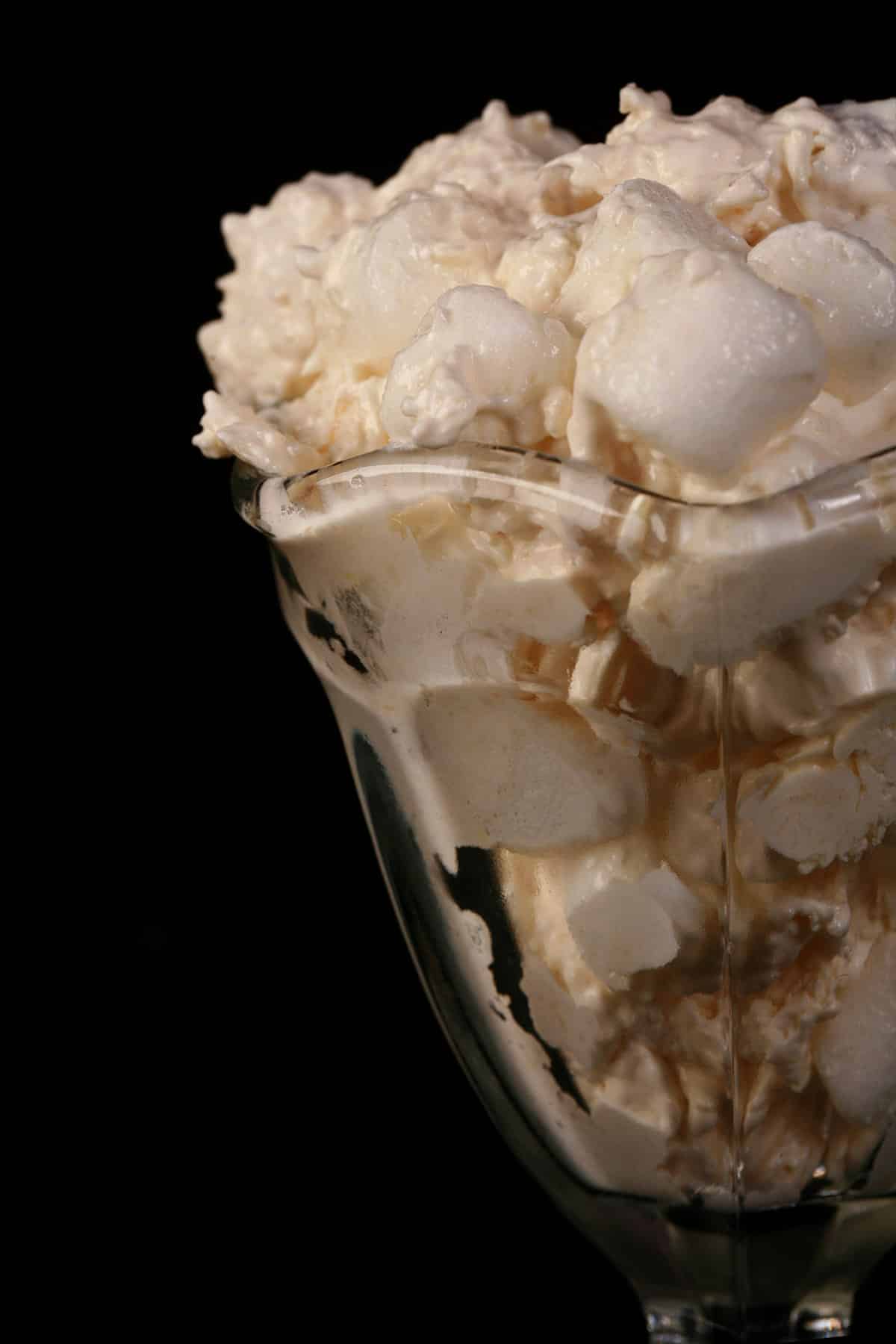 A close up photo of a serving of pina colada fluff in a tulip glass.