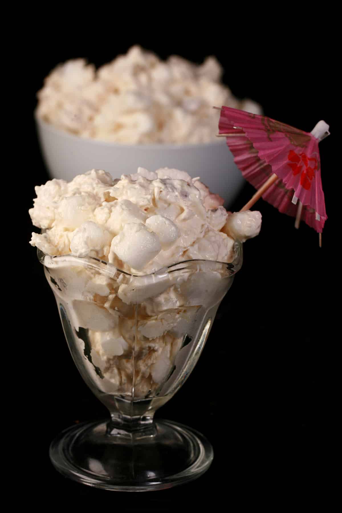 Pina colada fluff in a tulip glass with a pink cocktail umbrella sticking out.