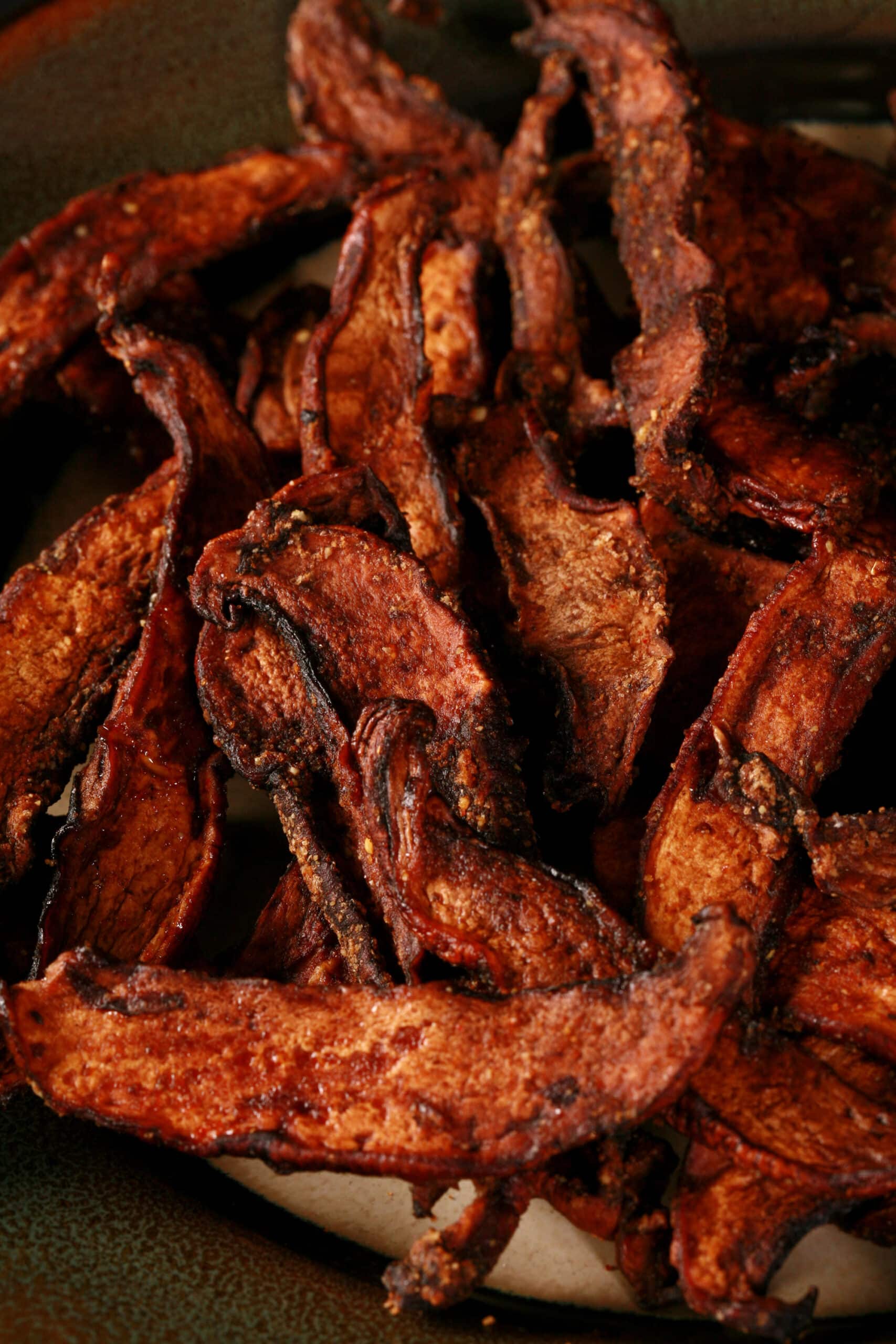 A plate of homemade mushroom jerky made from portabello mushroom slices.