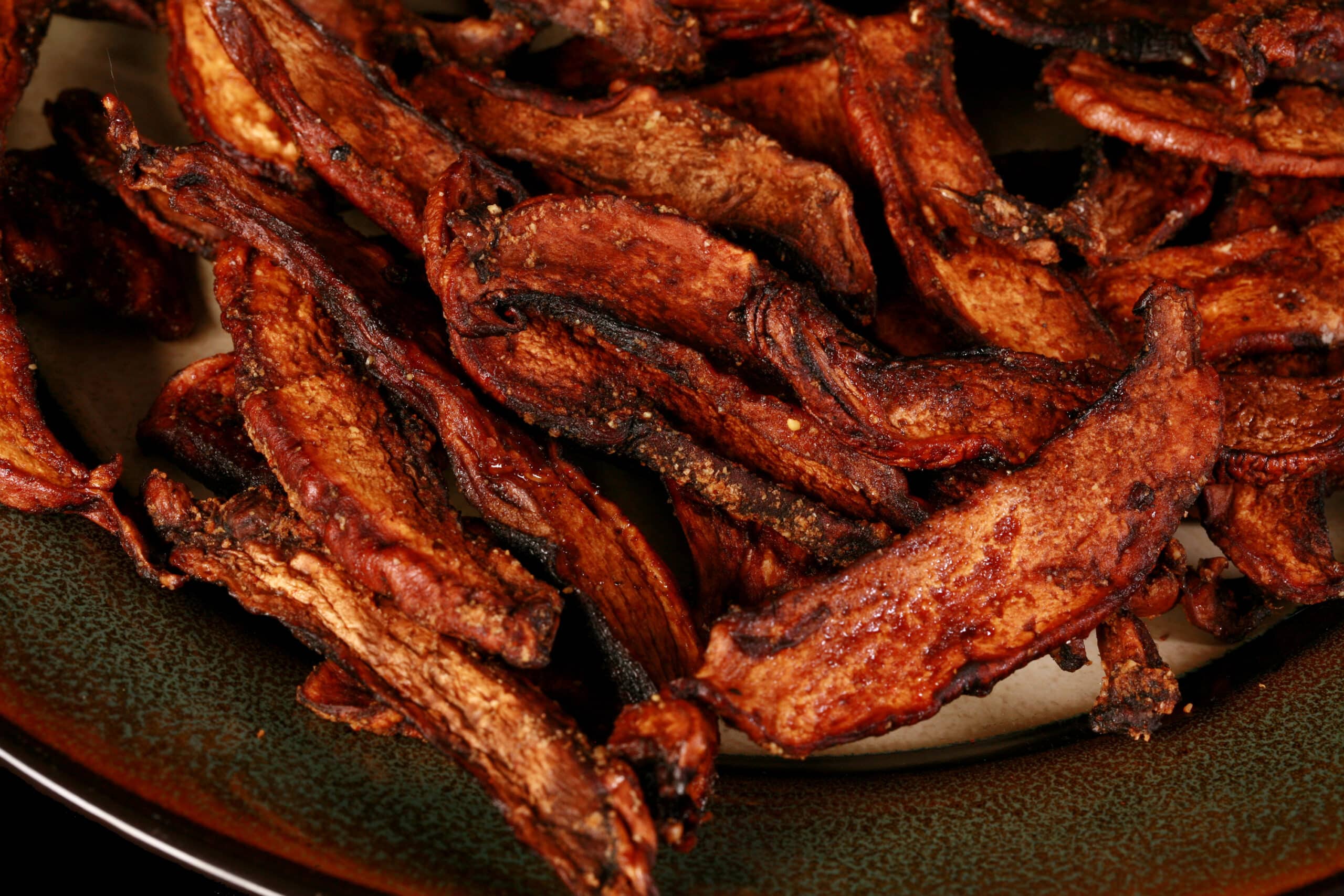 A plate of homemade mushroom jerky made from portabello mushroom slices.