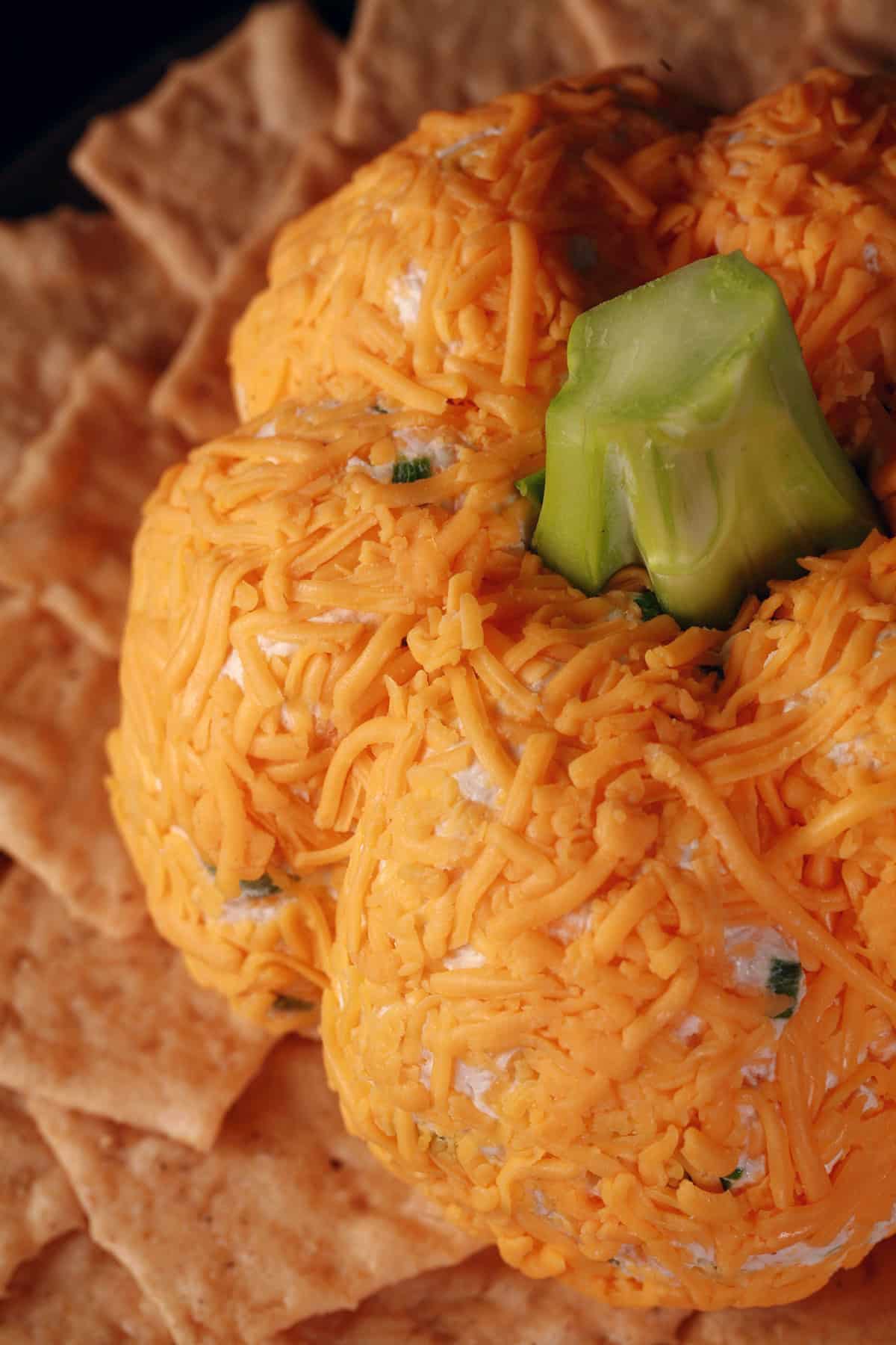 A Thanksgiving pumpkin cheese ball on a plate with crackers.