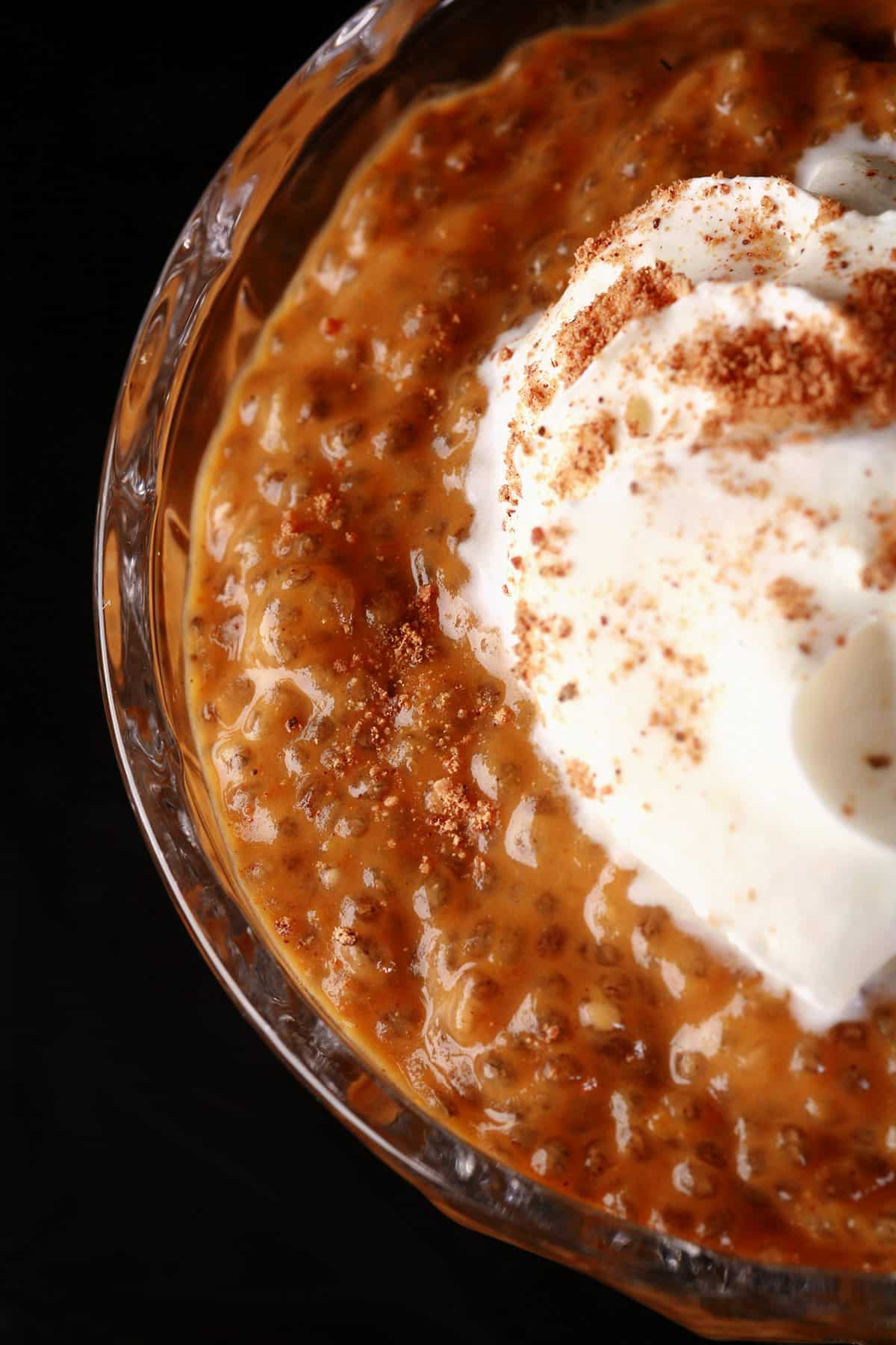 Pumpkin Chia Seed Pudding in a glass cup, topped with whipped cream and nutmeg.