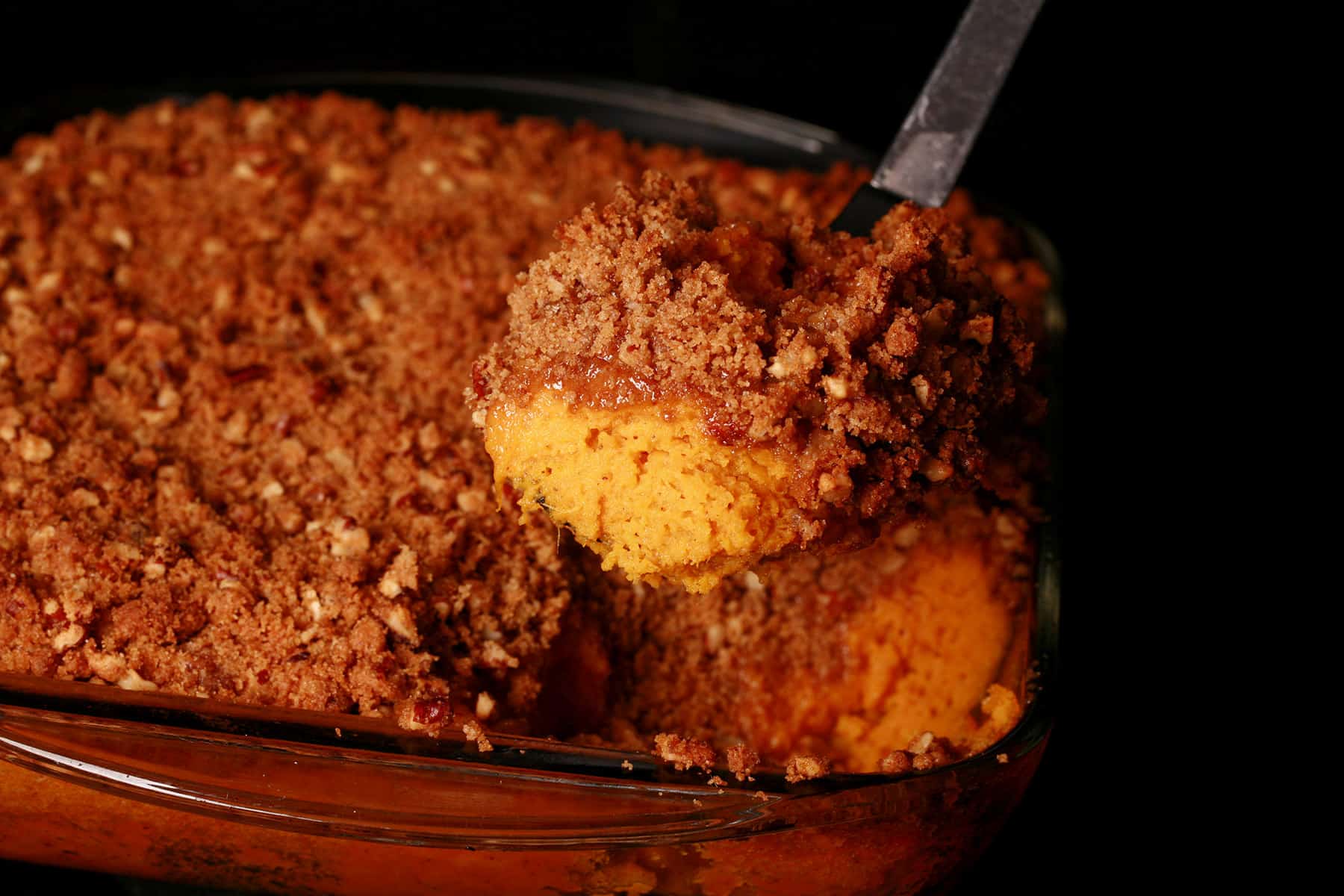A pan of sweet potato souffle with a scoop of it being spooned out.