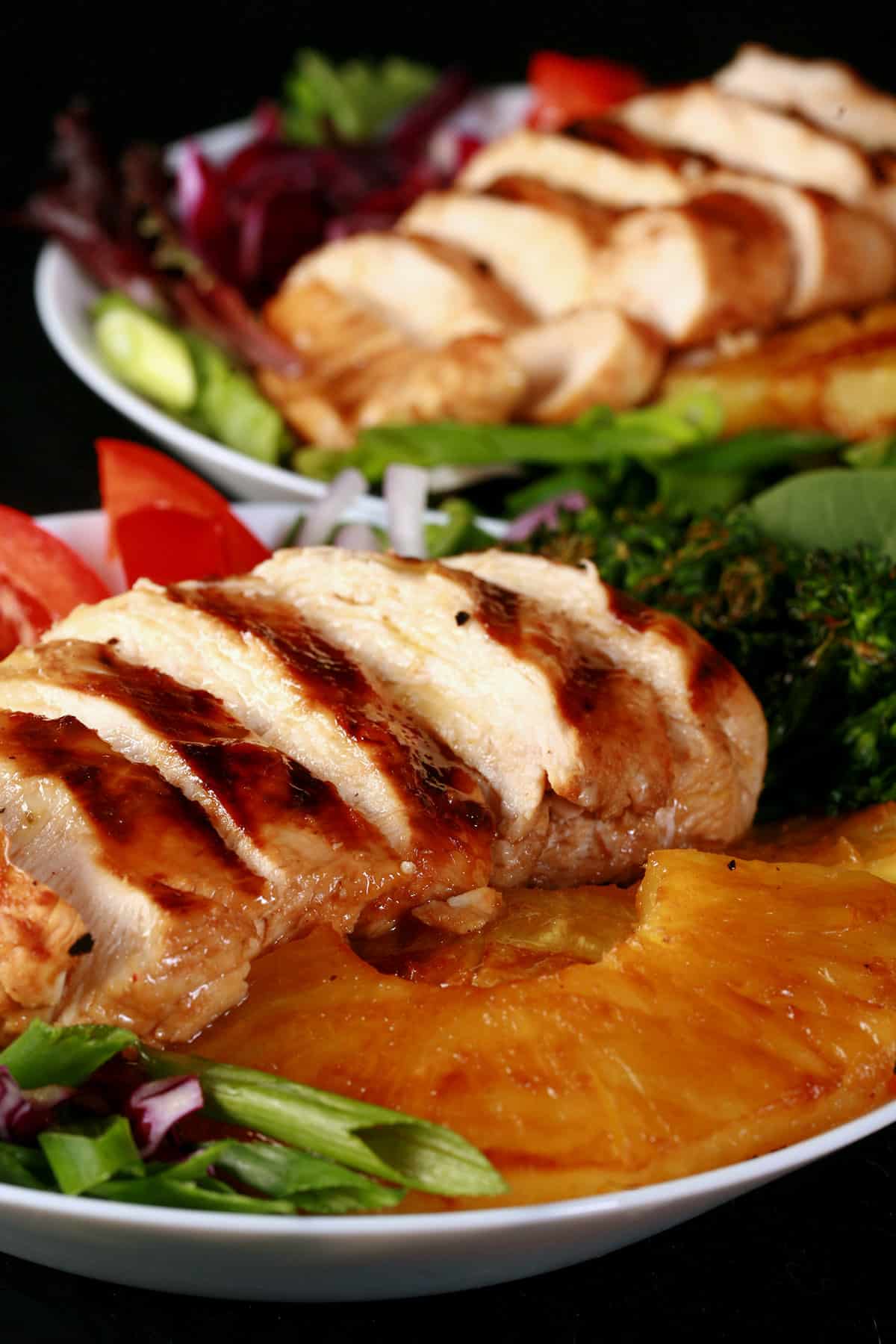 Two grilled chicken teriyaki salads with fresh pineapple.
