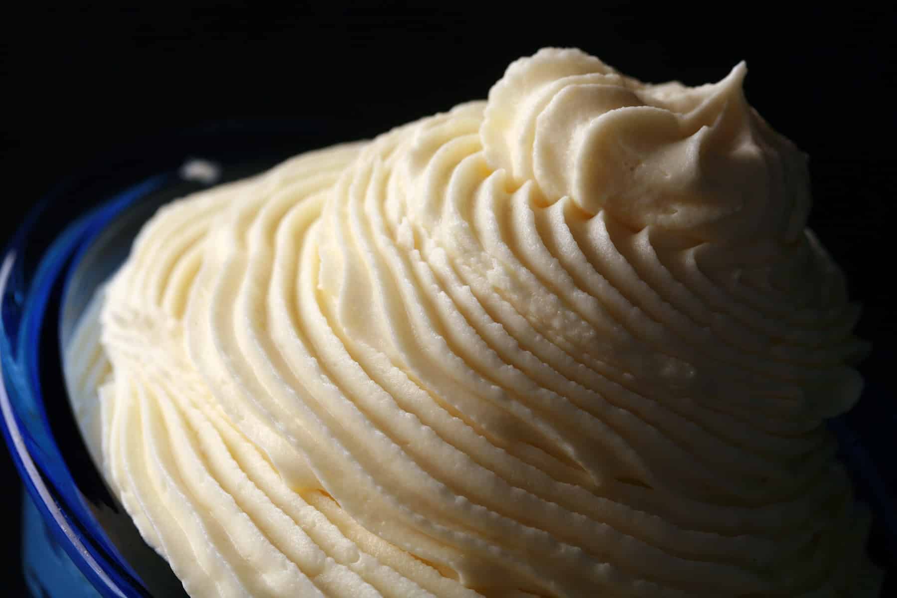 A tall swirl of white chocolate whipped ganache in a small bowl.