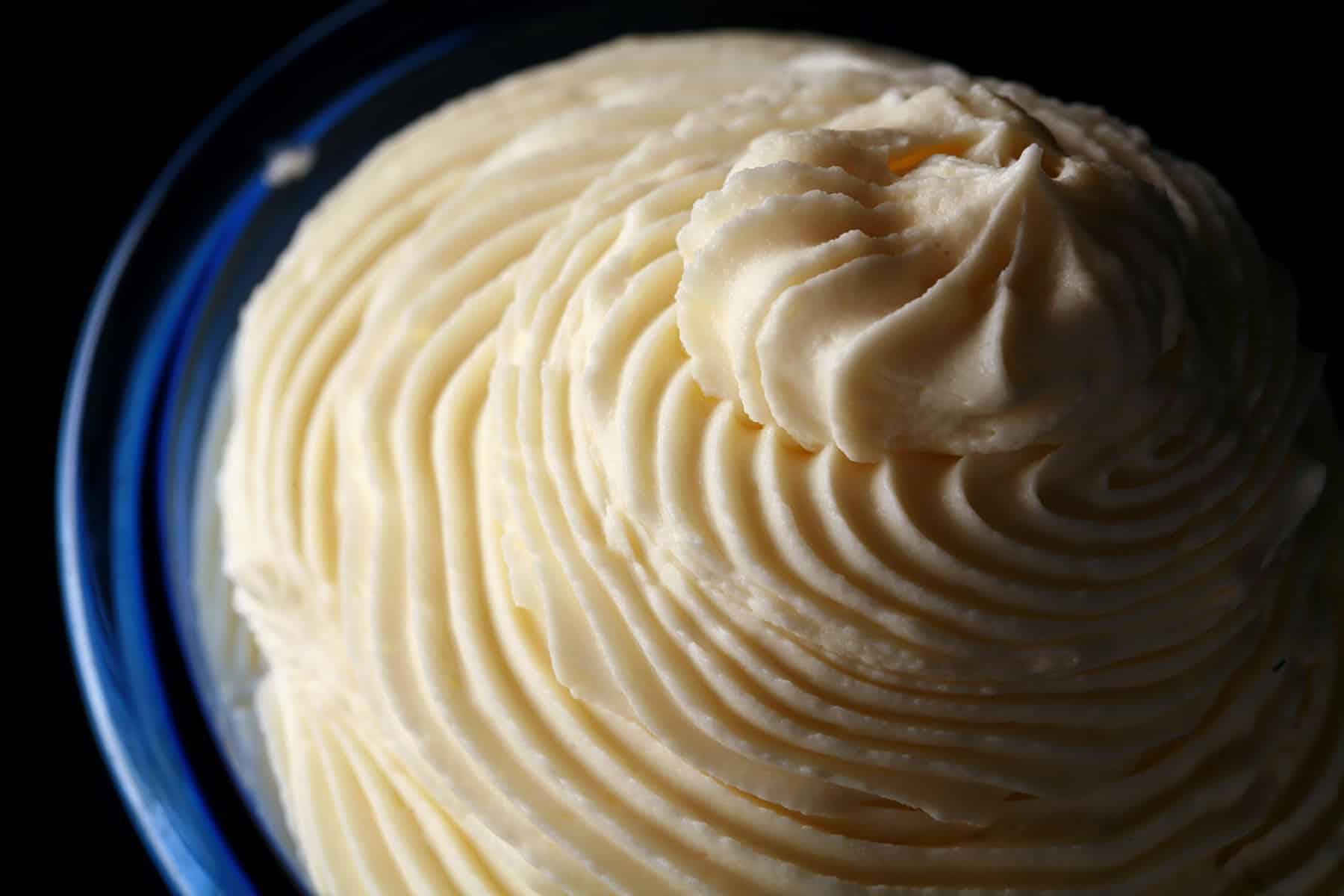 A tall swirl of whipped white chocolate ganache in a small bowl.